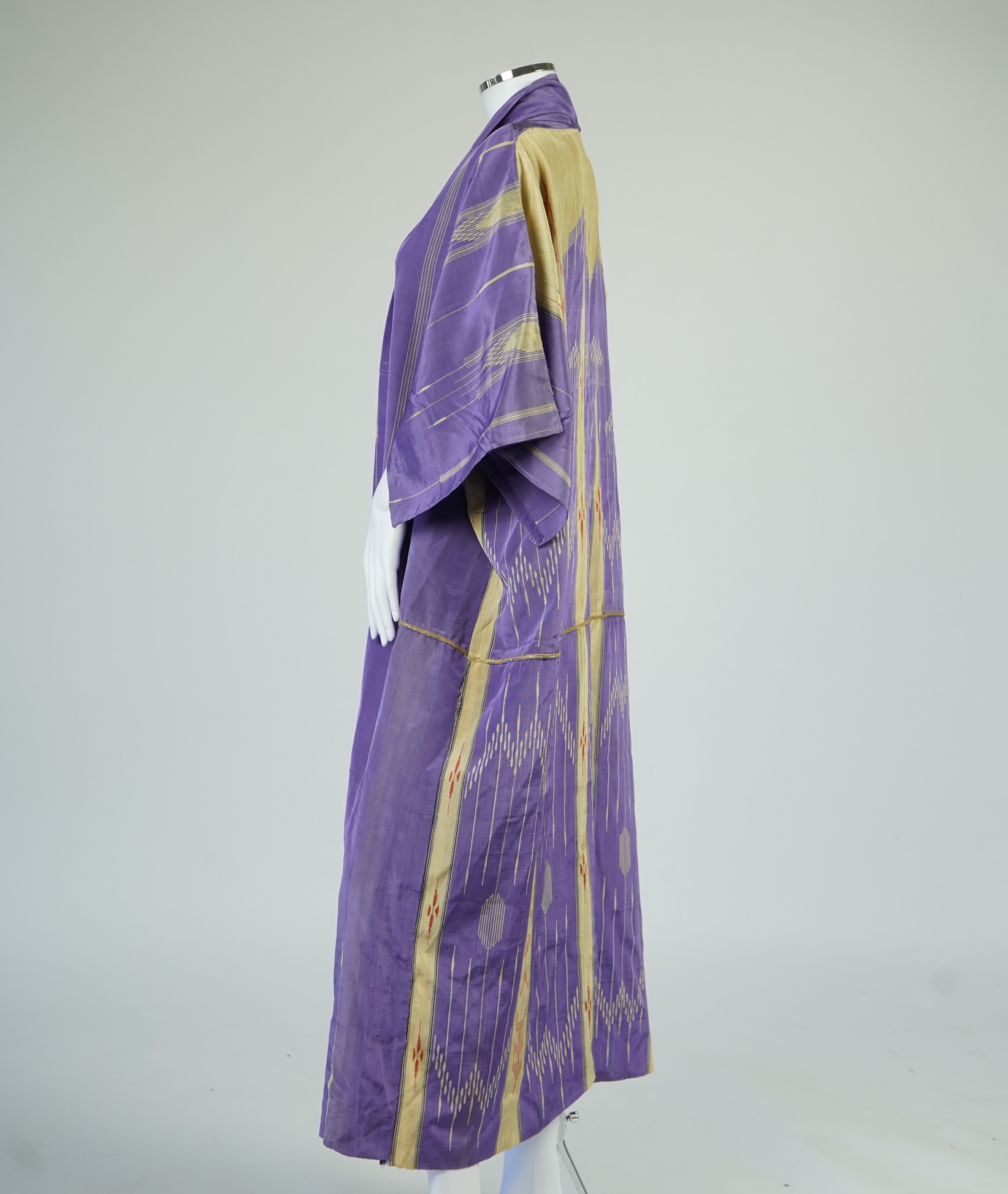 An early 20th century Syrian hand woven silk coat. Woven with stripes and geometric shapes in purple and yellow and red., 130 cm long. Condition - good, colours and fabric strong.